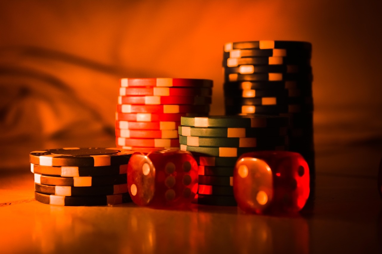 Stacks of casino chips and ruby dice in warm light