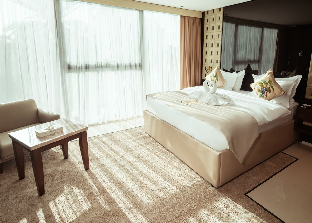 Bright boutique hotel room with ivory bedding and armchair