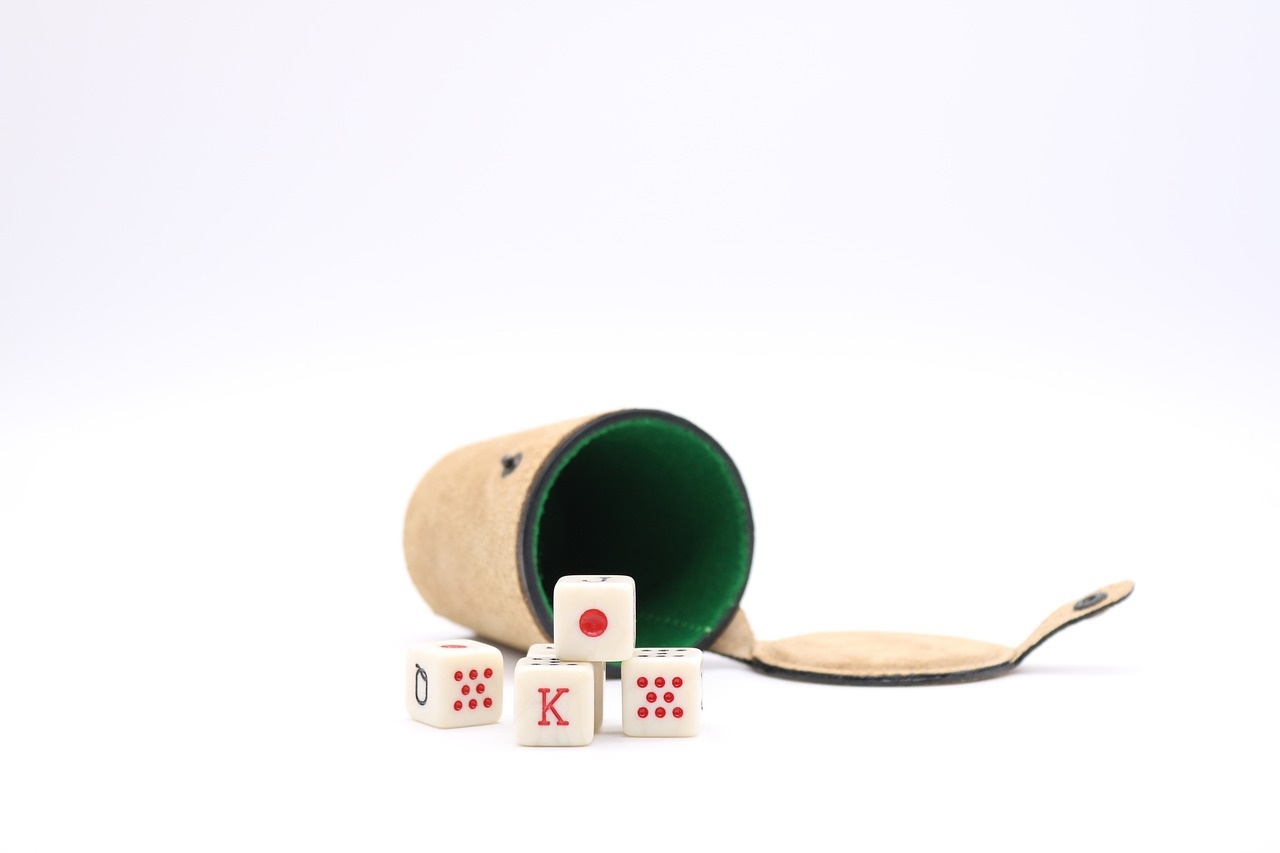 Leather dice cup and poker dice on a pale surface